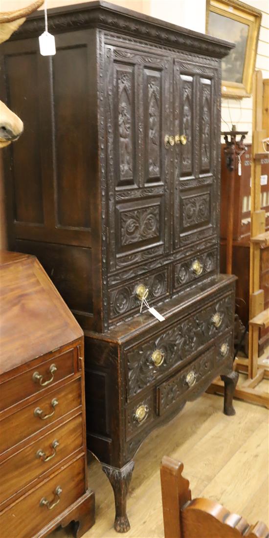 An 18th century large oak cupboard, fitted doors over one long and five short drawers, all later carved with figures and foliage W.112c